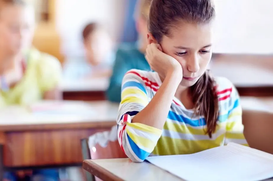Niña distraída y desmotivada en clase durante una actividad escolar