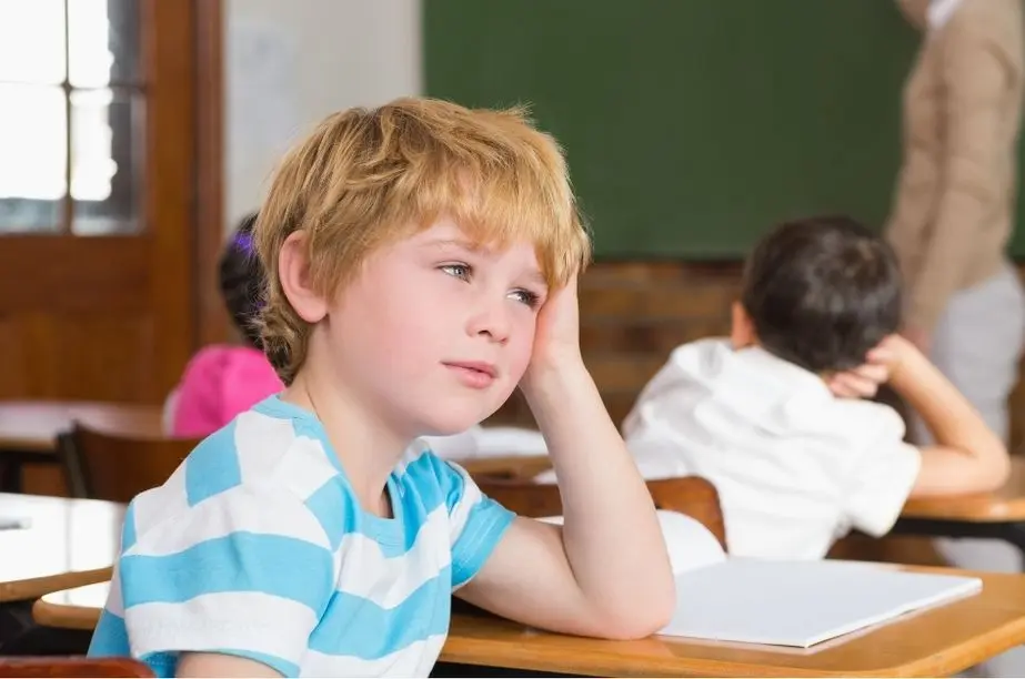 Niño distraído y aburrido en clase durante una actividad escolar