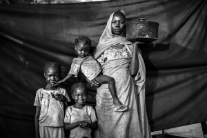 Magbola Alhadi, de 20 años, y sus tres hijas posan para un retrato en el campo de refugiados de Jamam en el condado de Maban, Sudán del Sur, el 11 de agosto de 2012. Magboola y su familia resistieron bombardeos aéreos durante varios meses, pero decidieron que era hora de abandonar su pueblo de Bofe la noche en que los soldados llegaron y abrieron fuego. Con sus tres hijas, viajó durante 12 días desde Bofe hasta la ciudad de El Fudj, en la frontera del sur de Sudán. La cosa más importante que Magboola pudo traer con ella es la cacerola que sostiene en esta fotografía. No era la olla más grande que tenía en Bofe, pero era lo suficientemente pequeña para viajar con ella, y lo suficientemente grande como para cocinar sorgo para ella y sus tres hijas (de izquierda a derecha: Aduna Omar, 6, Halima Omar, 4, Y Arfa Omar, 2) durante su viaje. Foto © Brian Sokol. ACNUR