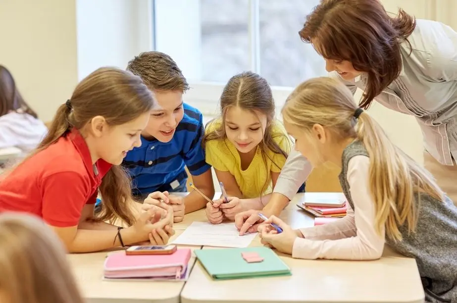 Niños resolviendo adivinanzas en clase con la ayuda de su profesora.