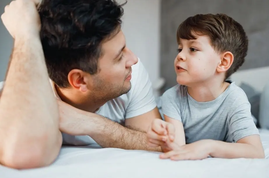 Padre jugando a las adivinanzas con un niño mientras conversan.