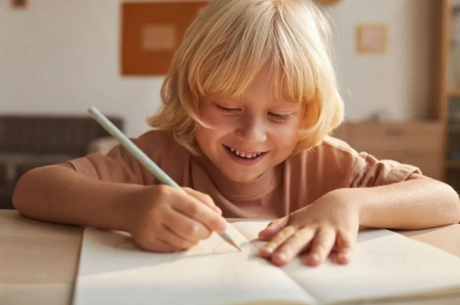 Niño escribiendo su propia adivinanza en un cuaderno.
