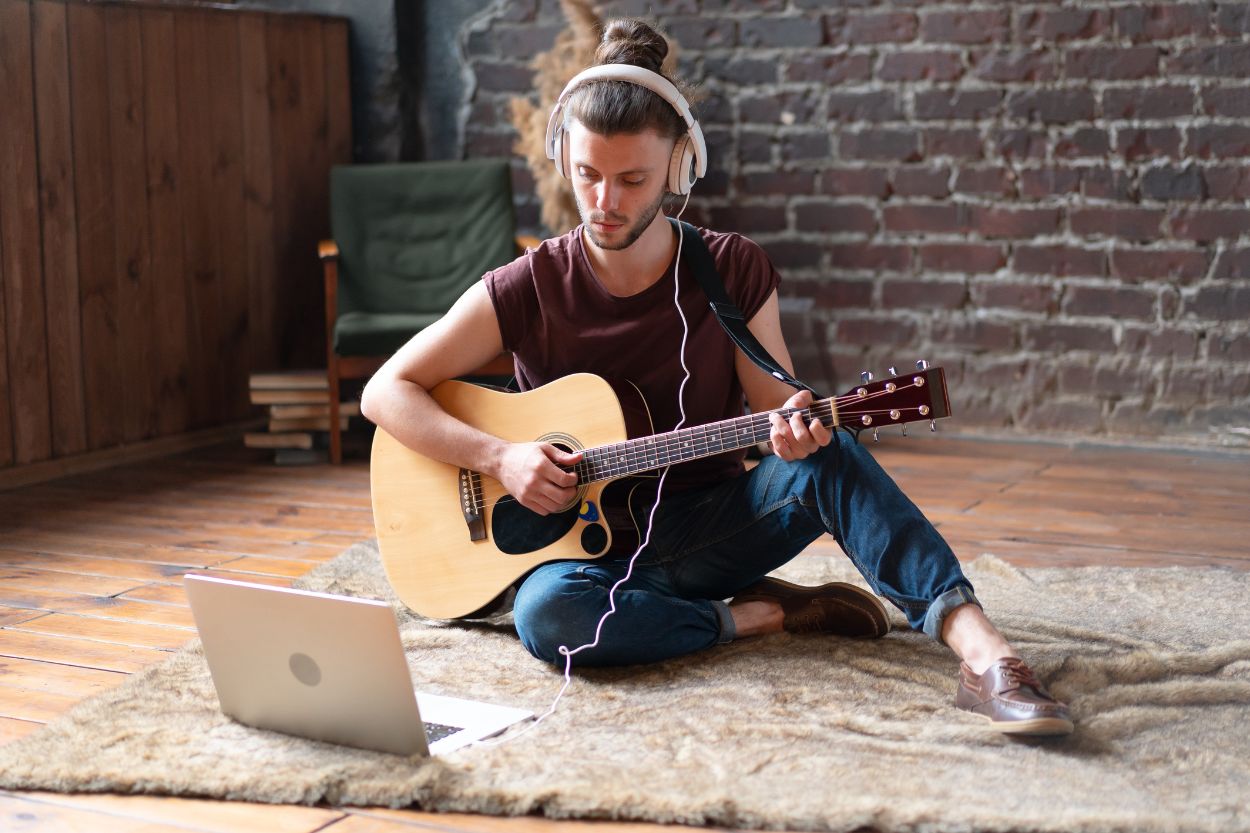 Adulto aprendiendo guitarra online con entusiasmo en casa