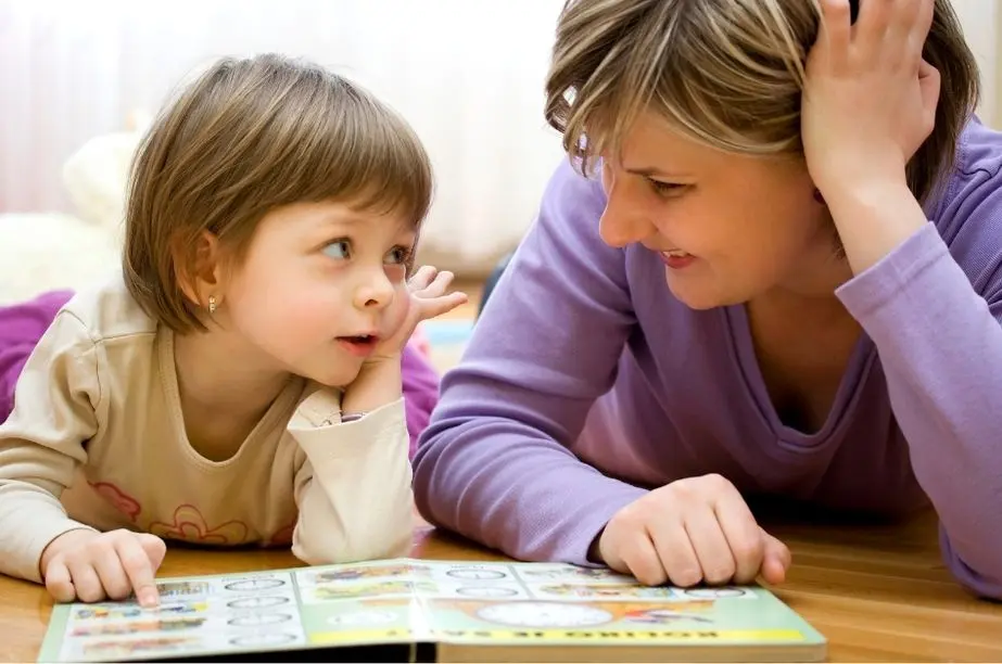 Madre y niña conversando durante la lectura de un libro