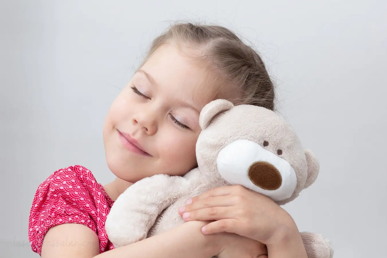 Niña abrazando un oso de peluche