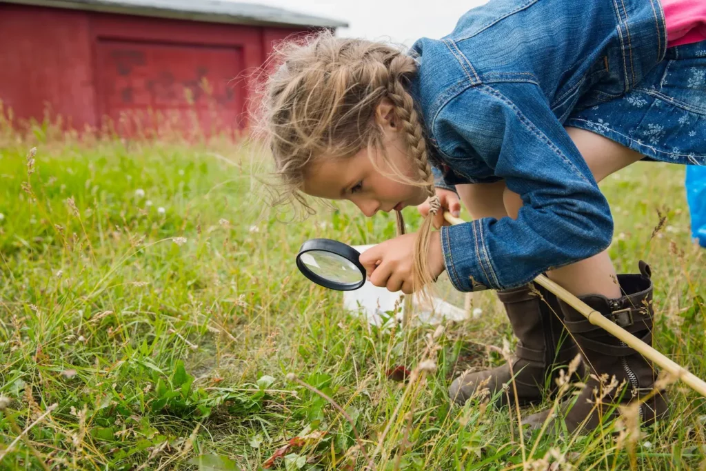Niña explorando la naturaleza con una lupa