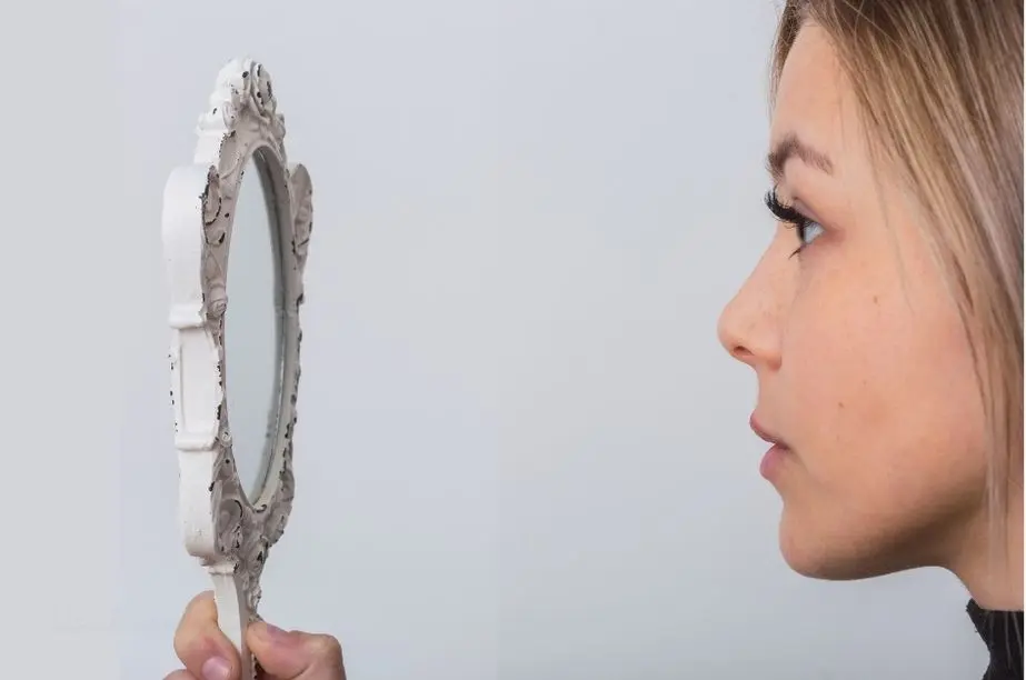 Mujer observándose en un espejo como representación de la autoconsciencia