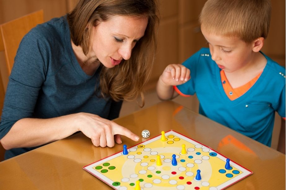 Madre explicando un juego de mesa a niño de 4 años