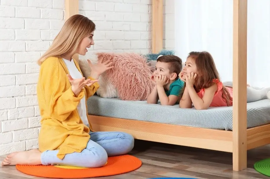 Madre enseñando trabalenguas a dos niños mientras practican el lenguaje jugando.