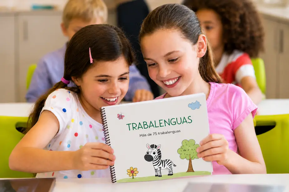 Dos niñas leen un cuadernillo de trabalenguas para niños y disfrutan practicando el lenguaje.