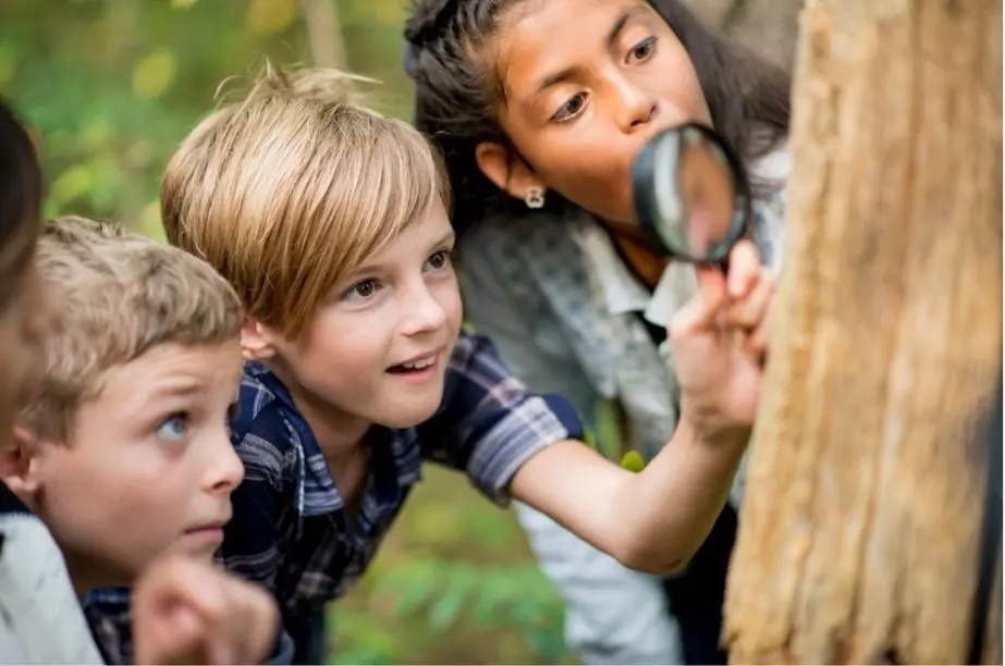 Niños explorando la naturaleza con una lupa