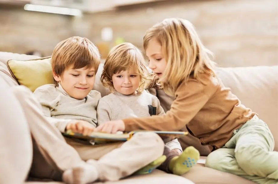 Tres niños pequeños leyendo juntos un libro