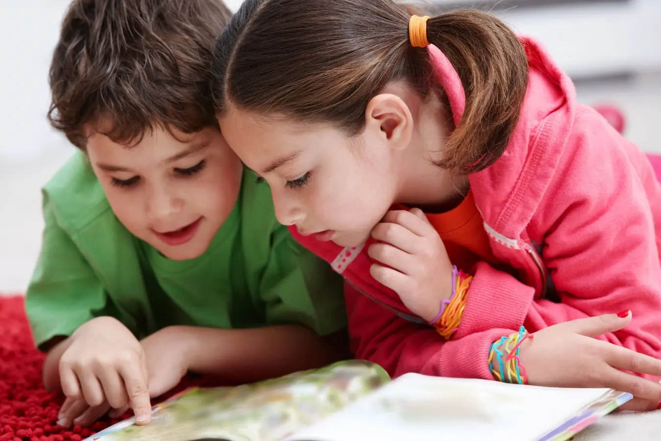 Dos niños leyendo juntos un libro informativo