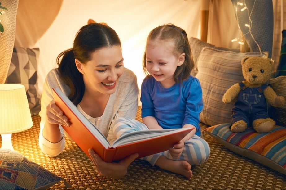 madre leyendo cuento infantil con niña pequeña antes de dormir