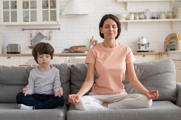 Respiración consciente en casa: madre enseñando al hijo ejercicios de calma