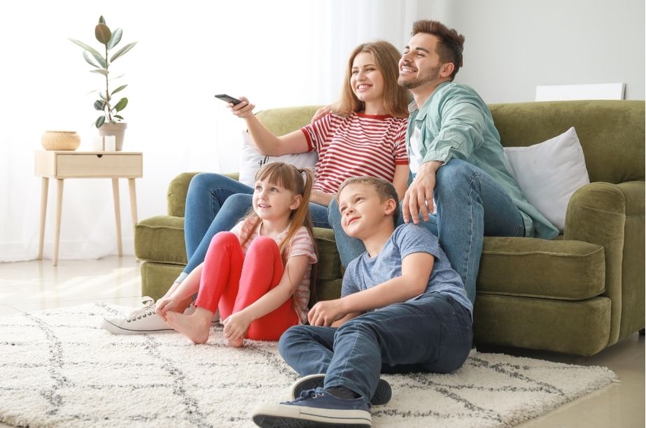 Familia viendo una película de aventuras en casa, ideal para disfrutar juntos la saga Jumanji