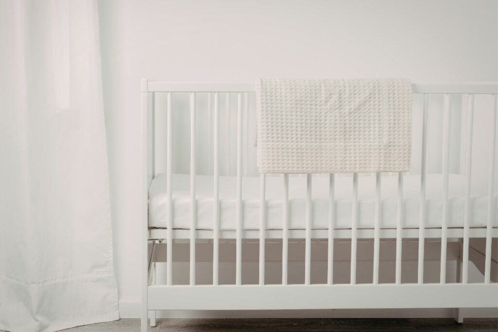 Cuna segura para recién nacido con barrotes blancos y colchón firme en un entorno tranquilo.