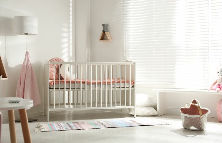 Habitación de bebé luminosa con cuna de barrotes blancos en un entorno doméstico tranquilo.