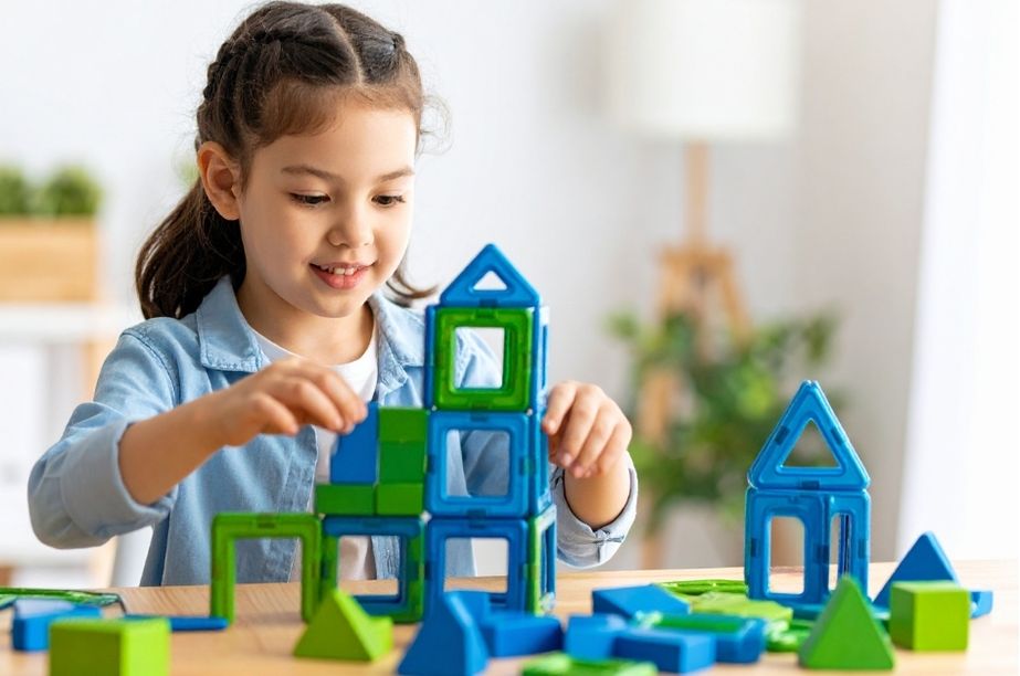 Niña construyendo figuras con piezas geométricas, representando el aprendizaje y la curiosidad en niños con altas capacidades