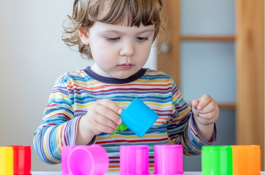 Niña pequeña jugando con piezas de colores y explorando formas
