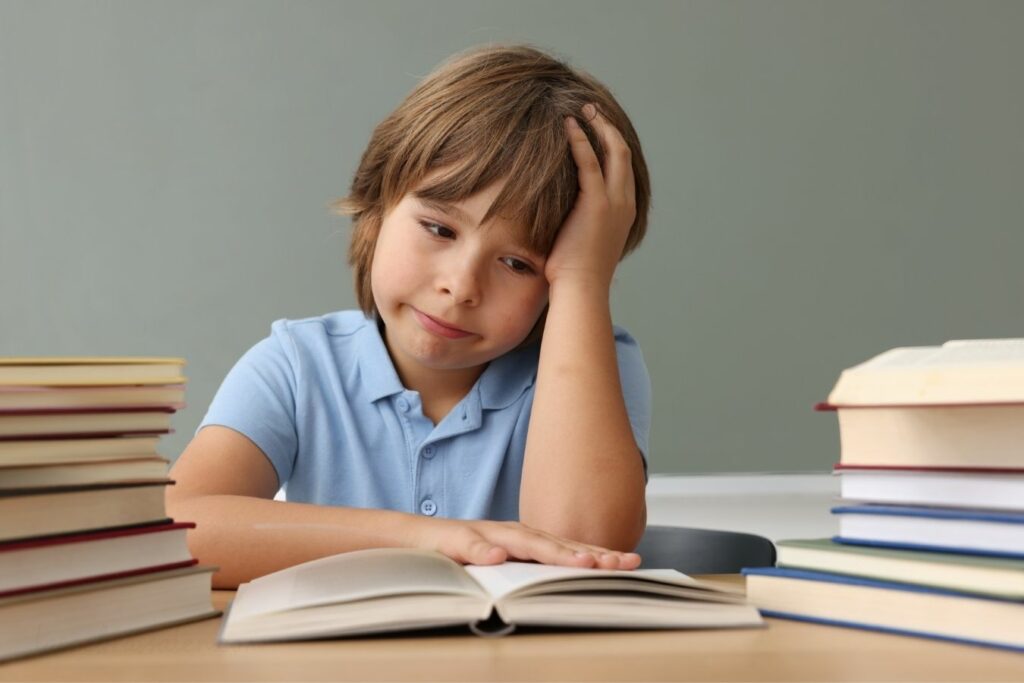 Niño de primaria con expresión pensativa y desmotivada frente a un libro abierto, relacionado con altas capacidades y bajo rendimiento escolar