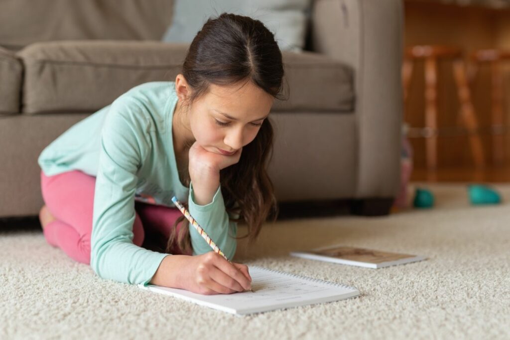 Niña de primaria concentrada escribiendo en un cuaderno, ejemplo de altas capacidades en niños de 7 a 10 años.