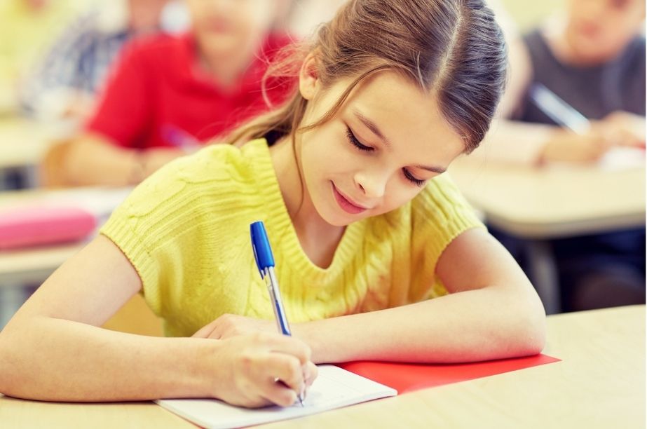 Niña de primaria concentrada escribiendo en clase, ejemplo de cómo pueden manifestarse las altas capacidades entre los 7 y 10 años.