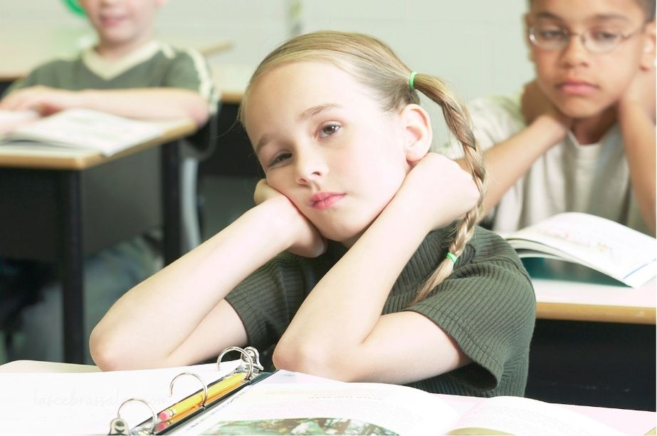 Niña de primaria con expresión de aburrimiento en clase, ilustrando el desajuste entre altas capacidades y entorno escolar