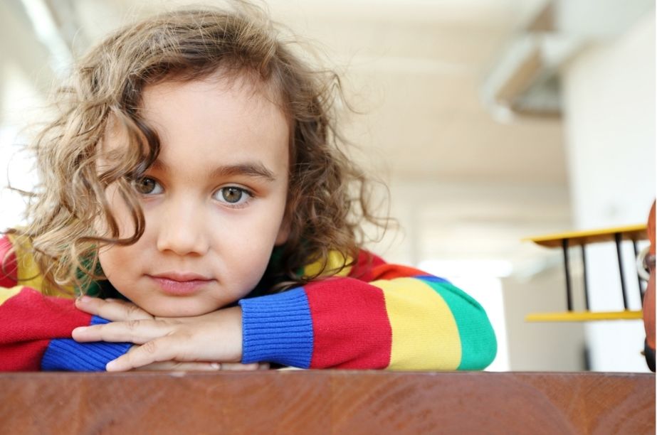 Niño en actitud tranquila y reflexiva, apoyado sobre una superficie y mirando al frente