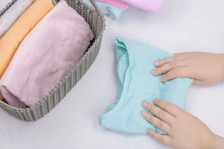 Manos doblando una camiseta infantil de algodón para el verano.