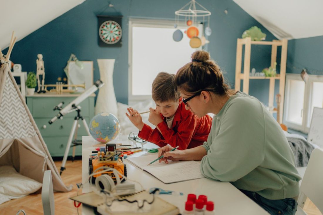 Madre acompañando a su hijo mientras trabajan juntos en casa explorando alternativas al homeschooling en España